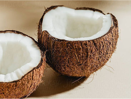 Two halves of a coconut on a beige background