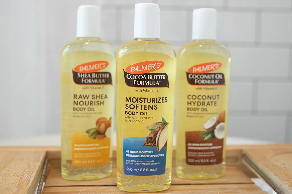 Three bottles of Palmer's body oils on a wooden surface with a white background