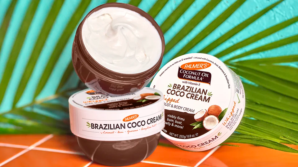 Two jars of Brazilian Coco Cream on a colorful surface with palm leaves in the background